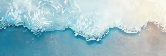 Blue ocean waves ripple over white sand with bright sun reflections and copy space
