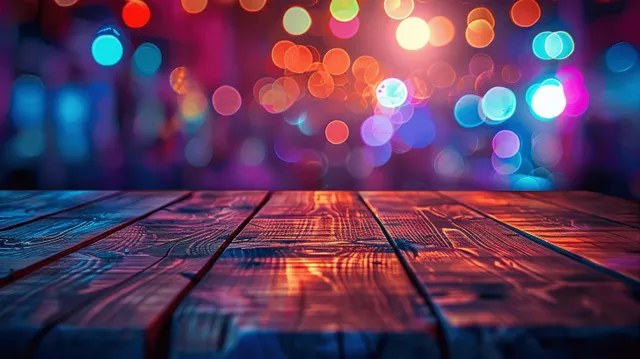 Wooden table top in the foreground with colorful blurred neon lights glowing in the dark background.