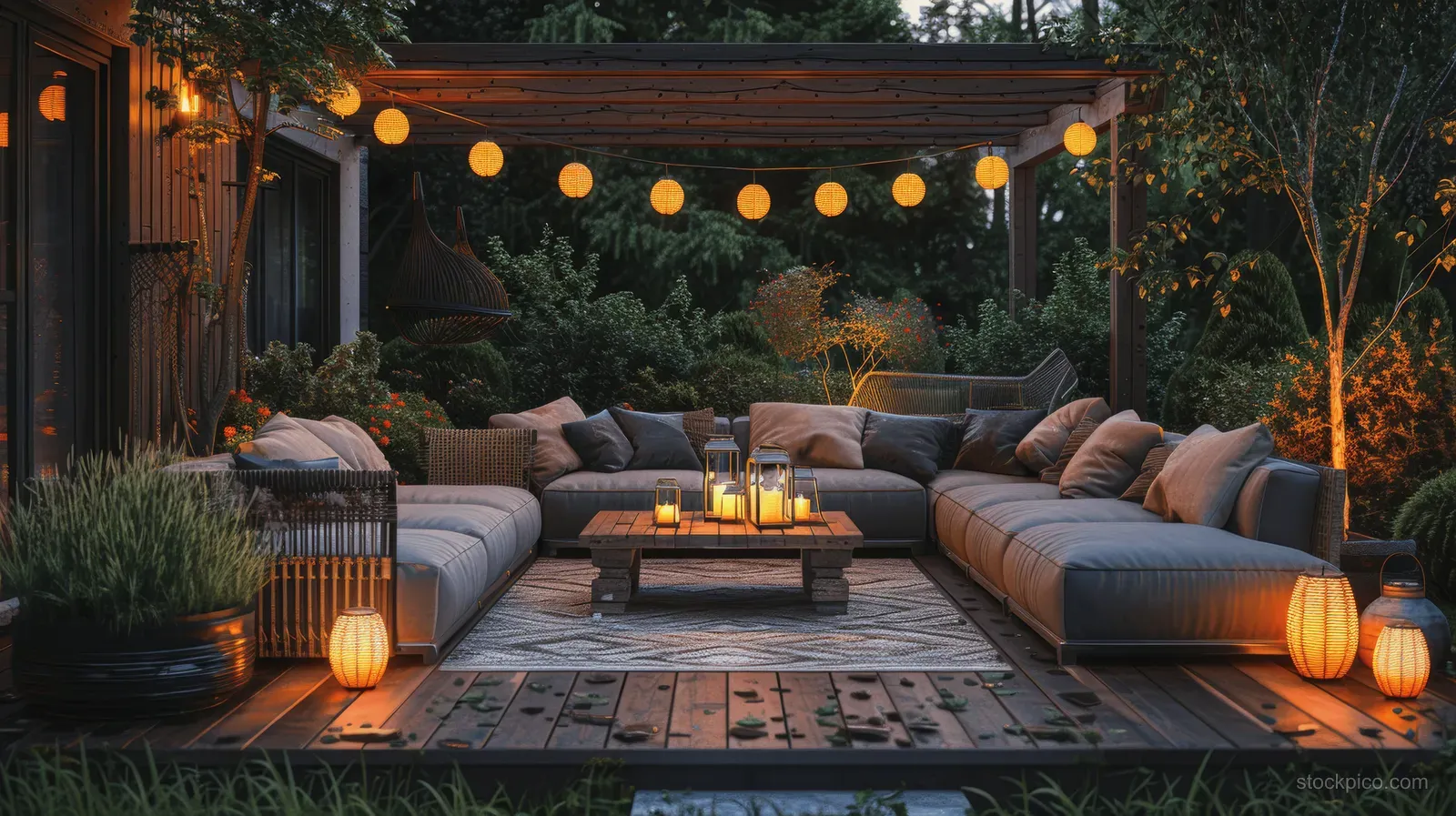 Curved outdoor sofas surround a firepit table on a night terrace lit by lanterns and string lights.