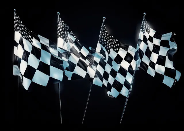 Four checkered racing flags wave on poles against a dark background with visible fabric motion and texture.