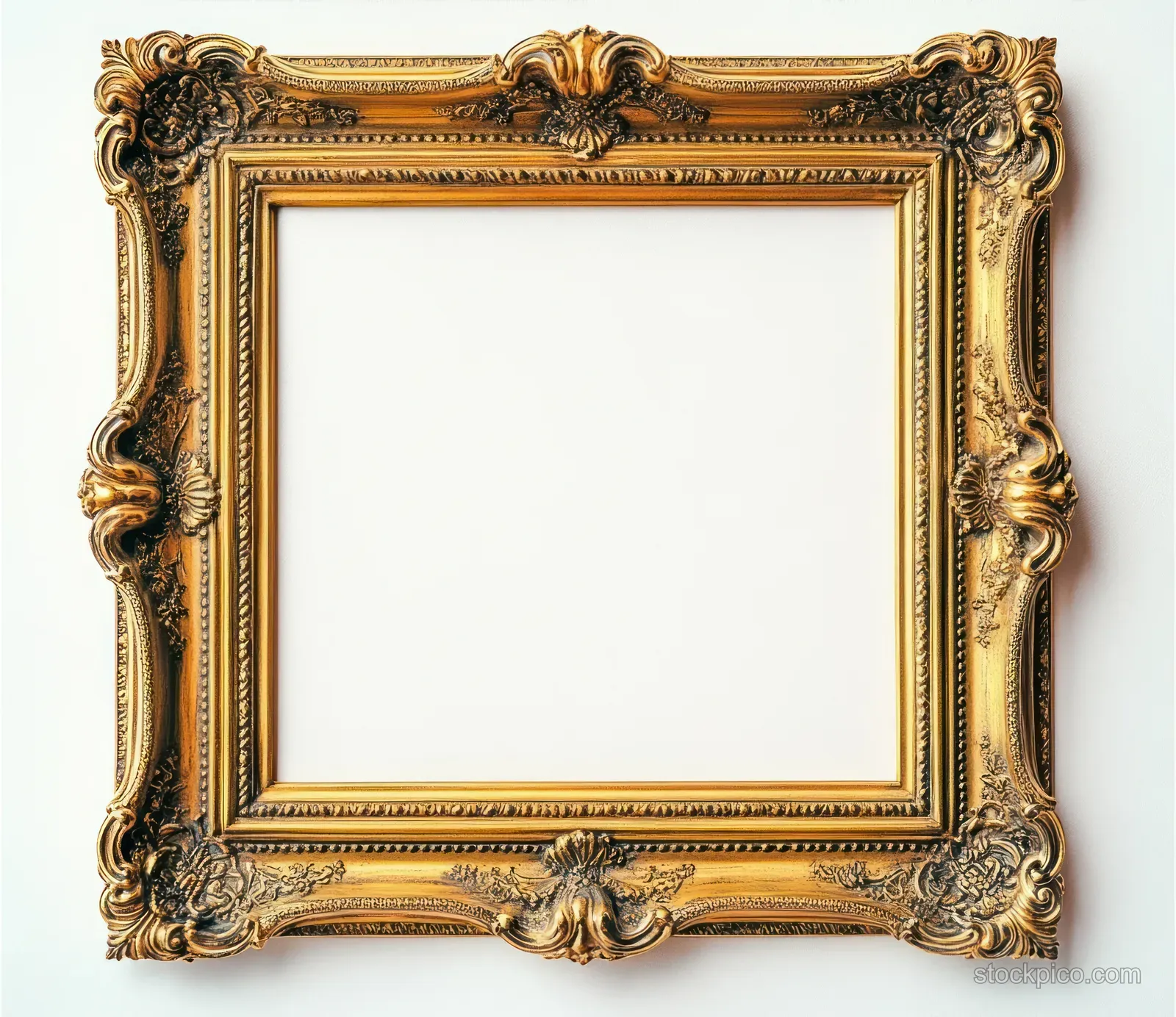 Empty ornate golden picture frame with carved floral scrollwork details on a plain white background.