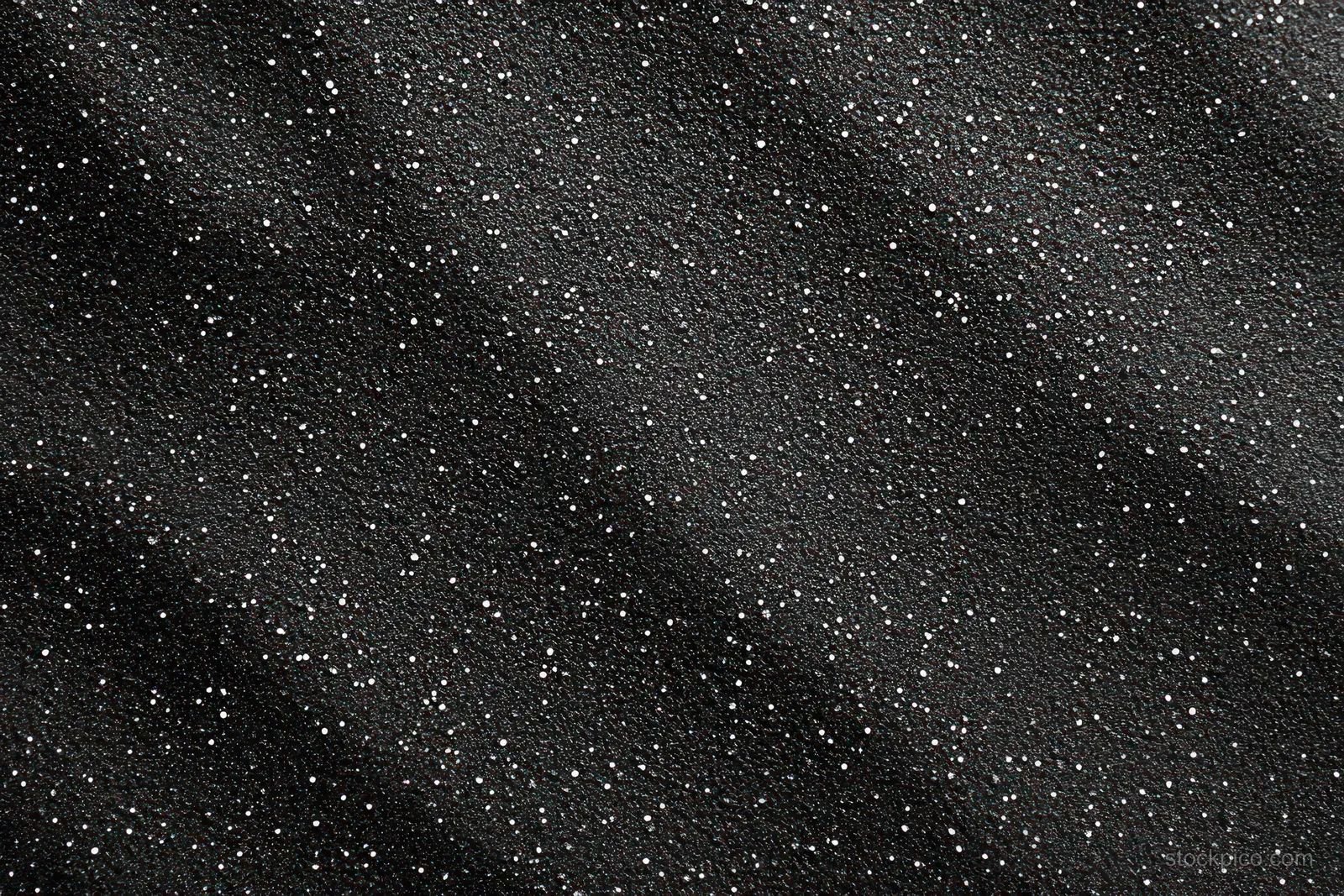 Close-up of a black textured surface scattered with small white specks.
