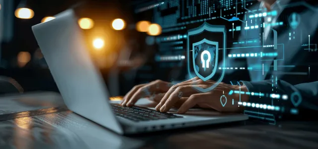 Hand typing on laptop with glowing encryption shield over network data streams