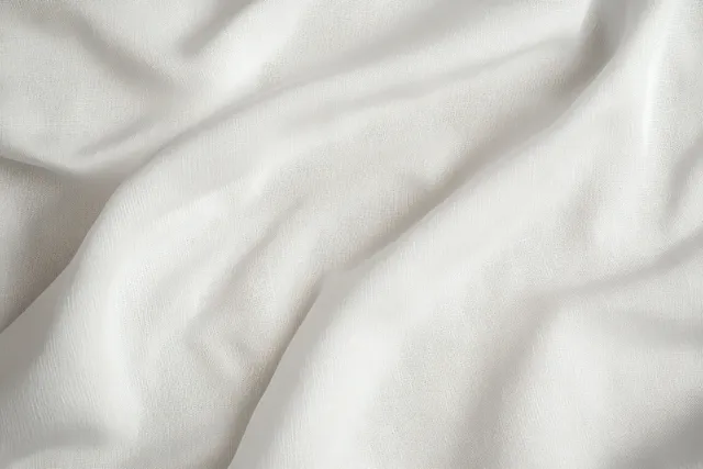 Close-up of white fabric folds with soft shadows and fine woven texture