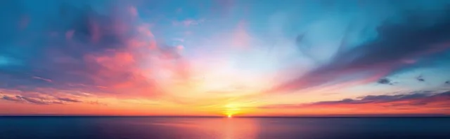 Panoramic sunset over calm ocean with glowing pink and purple clouds reflecting on the water.