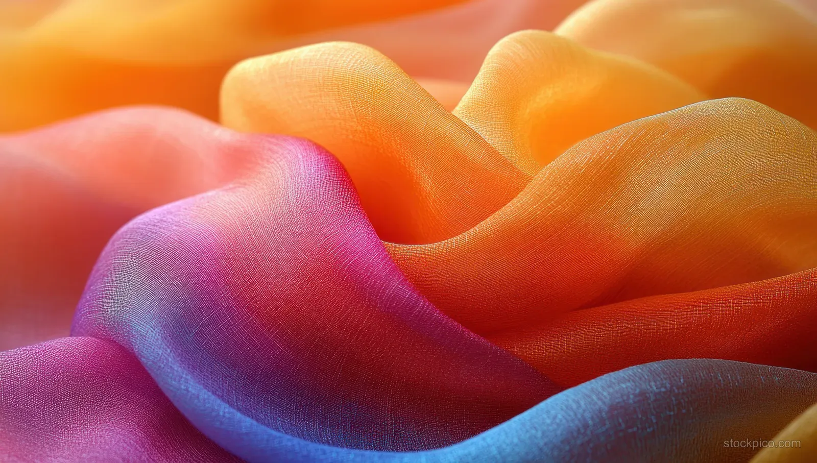 Colorful silk scarf fabric close-up with orange and purple folds on a warm orange background.