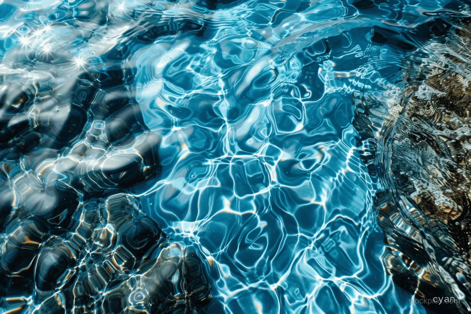 Top view of blue ocean water with ripples and bright cyan reflections across a textured surface.