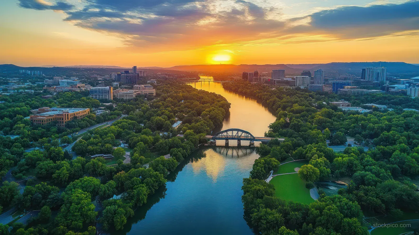 Aerial view of Chattanooga with a winding river, bridges, and city skyline under a glowing sunset.