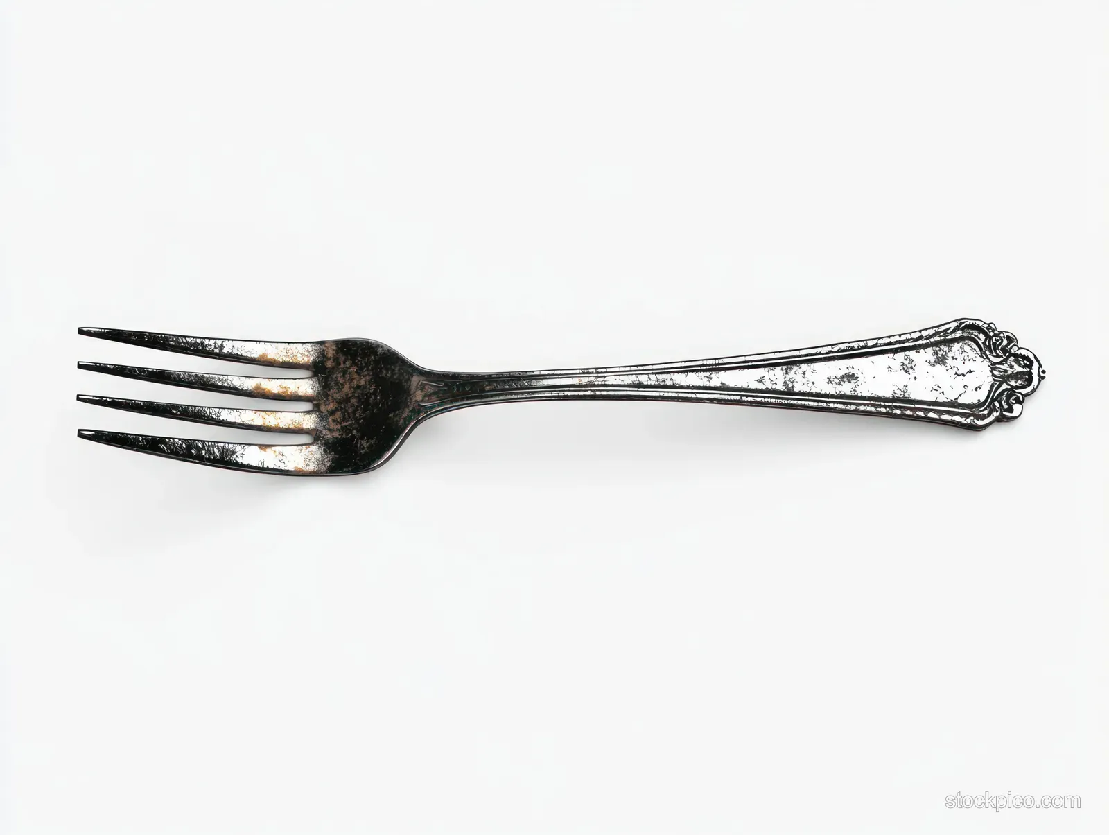 Tarnished metal fork with ornate handle isolated on a clean white background.
