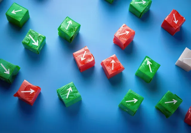 Green and red translucent cubes scattered on a blue surface with white directional arrows pointing different ways.