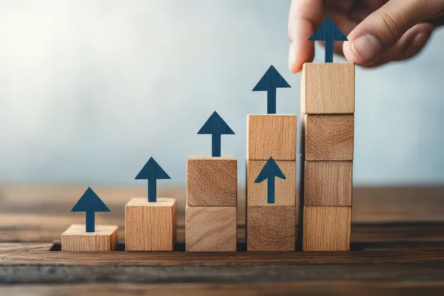 Hand stacking wooden blocks with upward arrows on career ladder concept