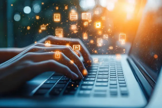 Close-up hands typing on laptop keyboard with floating chat icons in warm light