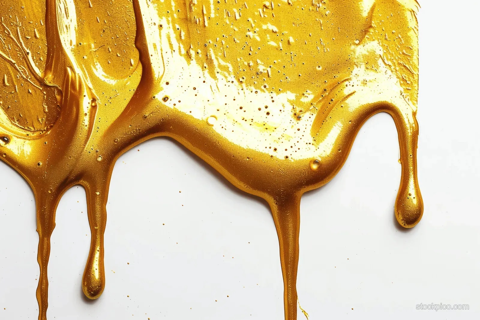Golden acrylic paint drips and pools on white paper with glossy streaks and scattered splatter.