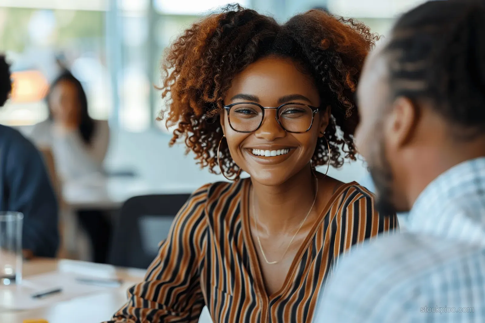 Smiling African American businesswoman leads a team meeting around a conference table in a modern office.