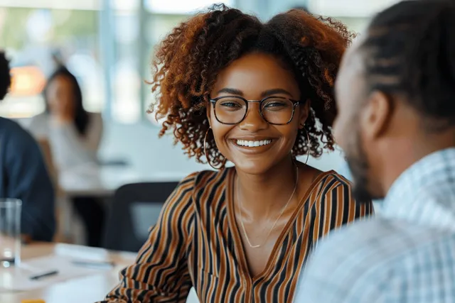 Smiling African American businesswoman leads a team meeting around a conference table in a modern office.