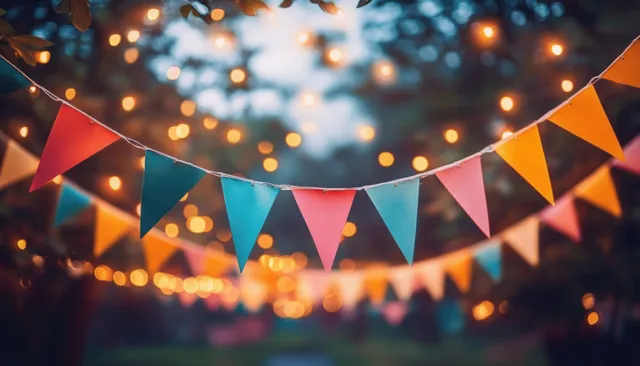 Colorful triangular bunting flags strung outdoors with warm lights bokeh backdrop