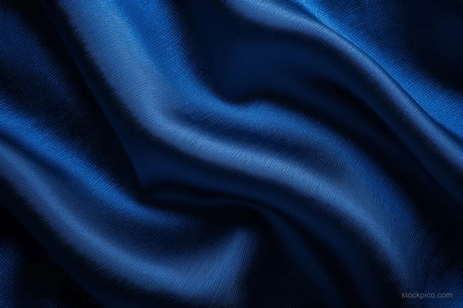 Dark blue silk fabric close-up with shiny highlights and flowing wavy folds.