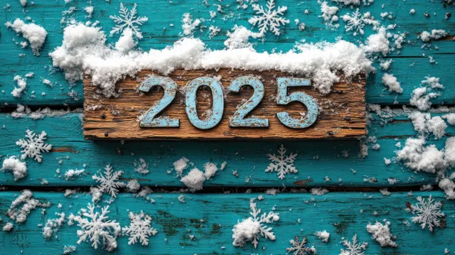 Snowflakes scatter around a wooden board reading 2025 on teal winter planks