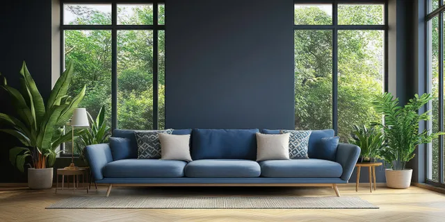 Blue sofa with patterned cushions in a bright minimal living room beside potted plants and large windows.