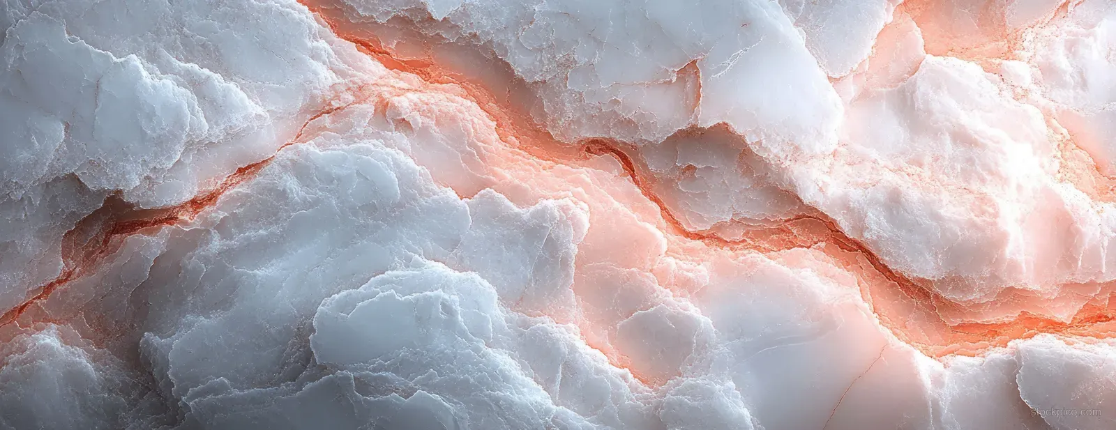 Closeup of glossy white marble with flowing pink and orange veins across the textured surface.