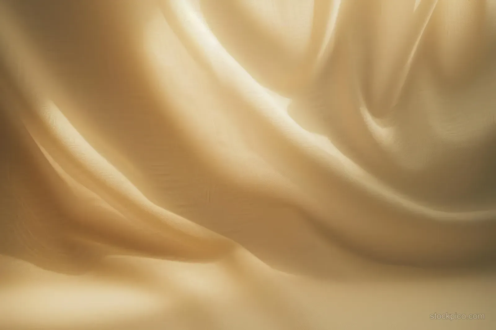 Beige fabric close-up with flowing folds, soft shadows, and warm light reflections.