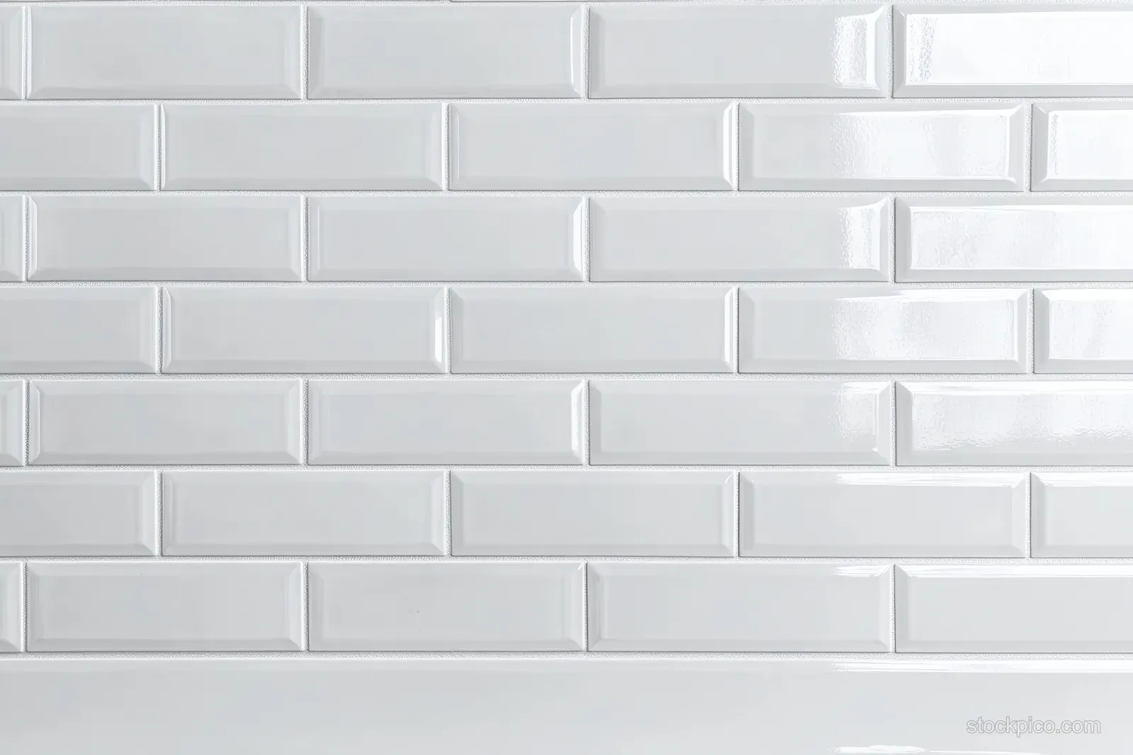 Glossy white subway tiles arranged in a classic brick pattern create a modern minimalist wall background.