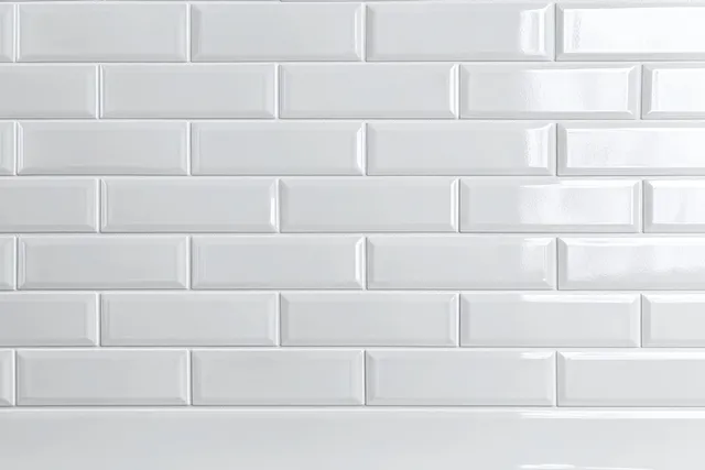Glossy white subway tiles arranged in a classic brick pattern create a modern minimalist wall background.