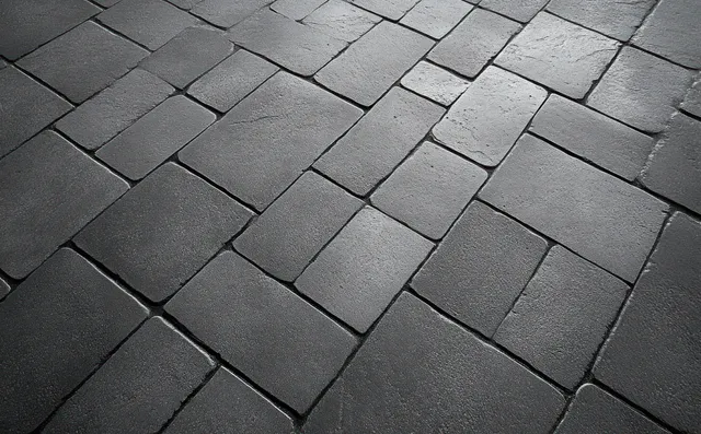 Wet gray stone pavement tiles in a staggered pattern with reflective highlights and visible grout lines.
