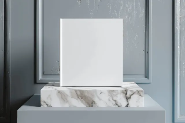 Blank white hardcover book cover placed on a marble pedestal in a minimalist room with soft shadows.