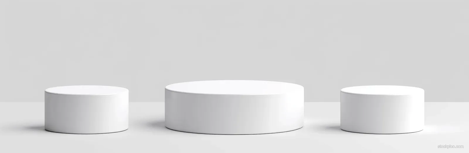 Three white cylindrical podiums sit on a gray background with soft shadows.