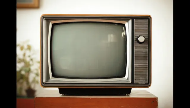 Vintage CRT television set shown front-on with a blank gray screen on a wooden table.
