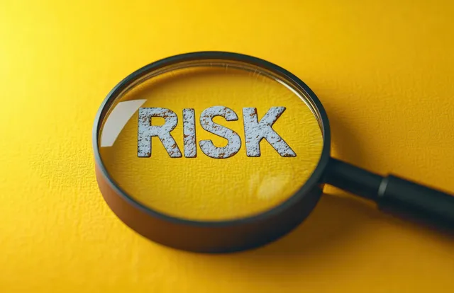 Magnifying glass enlarging the word RISK on textured yellow background for caution