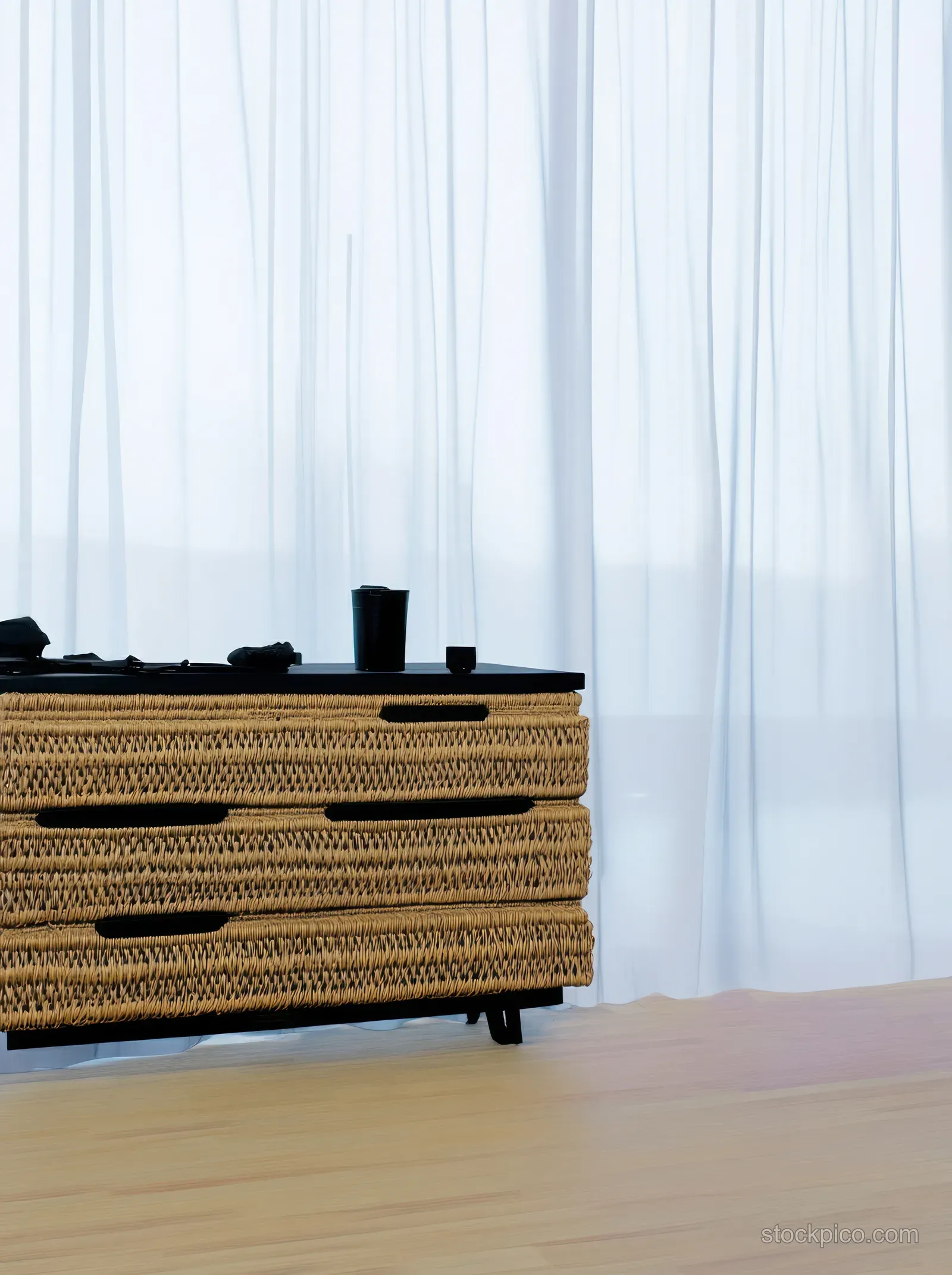 Rattan dresser in a Scandinavian living room with wooden flooring and daylight filtering through sheer curtains.