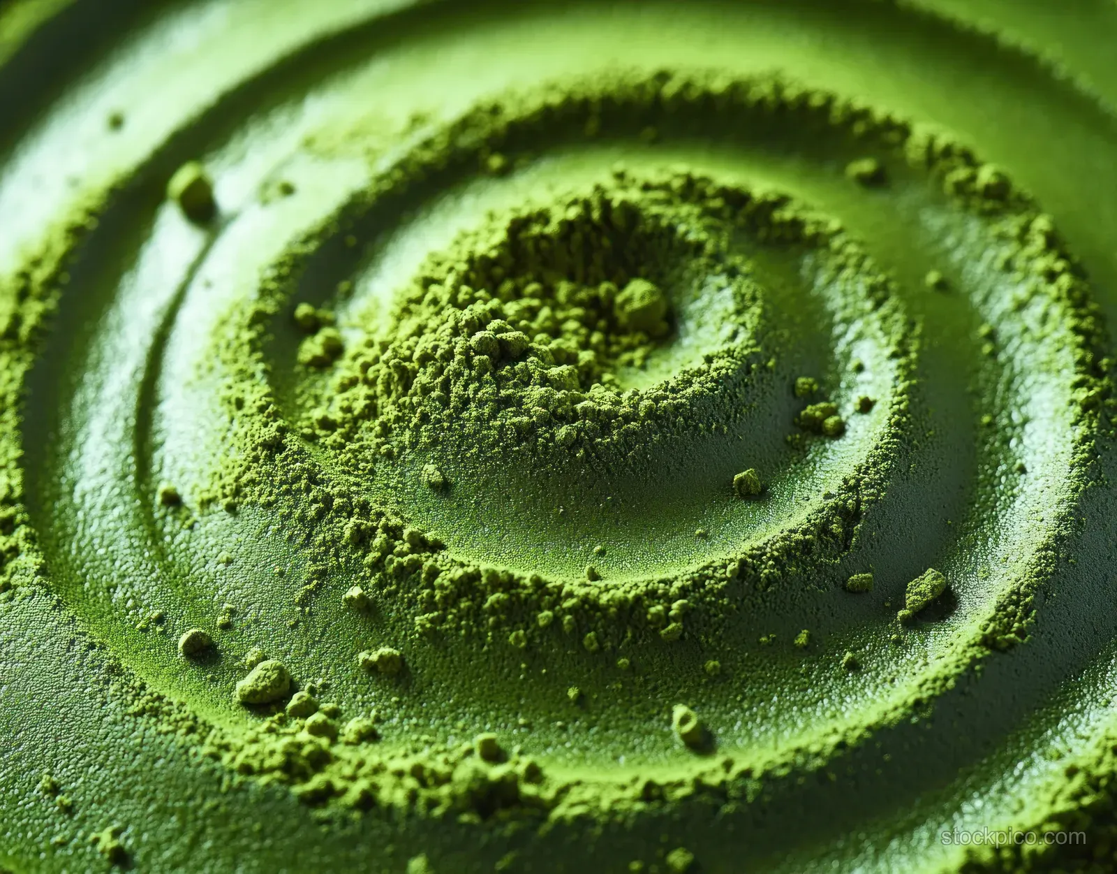 Macro view of bright green powder forming a spiral with visible granular texture and concentric rings.