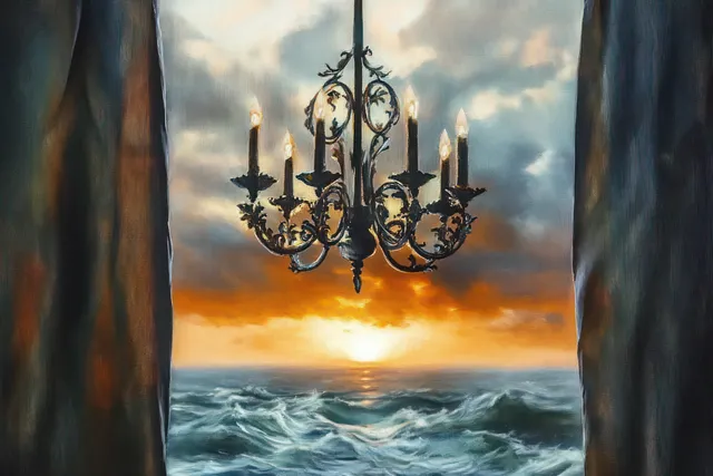 An ornate chandelier with lit candles hangs behind heavy curtains overlooking turbulent ocean waves at sunset.