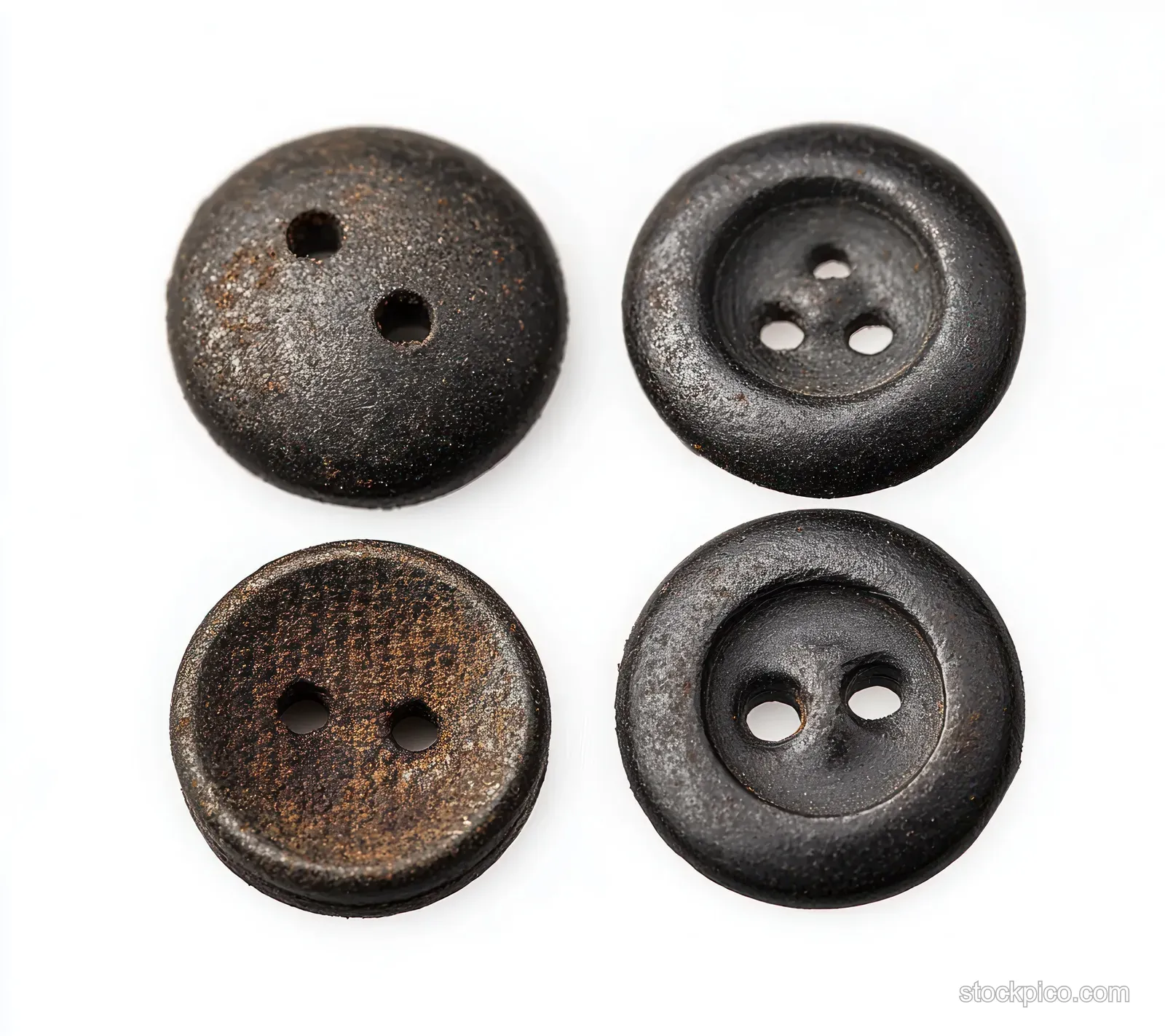 Four weathered buttons with two and four thread holes displayed on a white background.