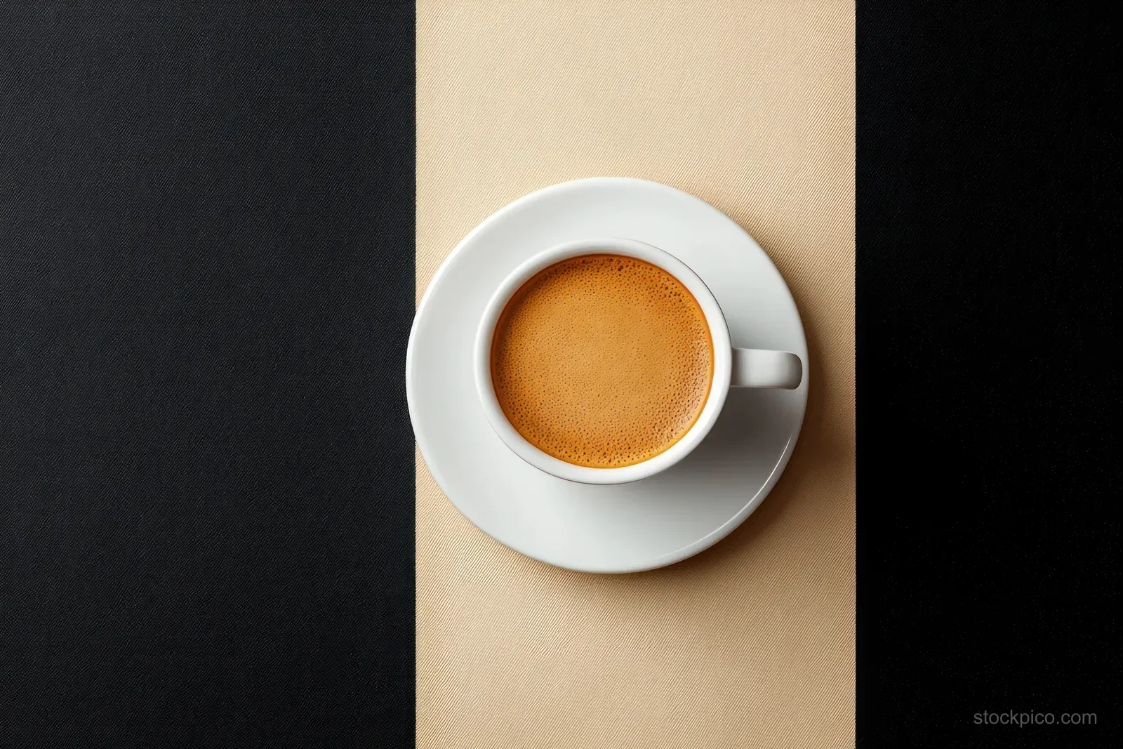 Top view of a white espresso cup and saucer with crema on a beige and black split background.