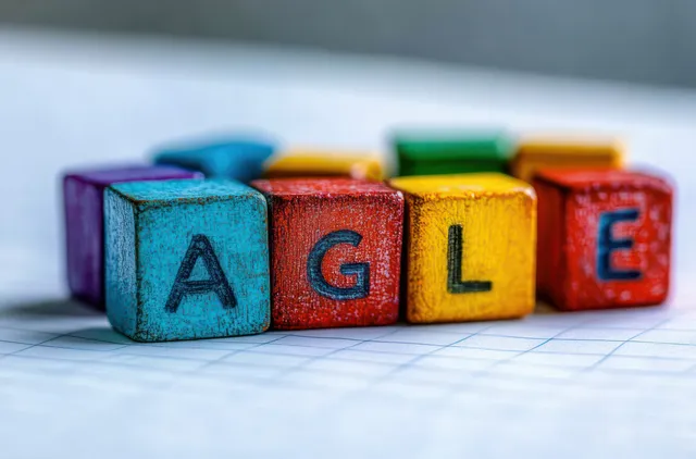 Colorful wooden blocks spell EAGLE on grid paper with a soft blurred background behind them.