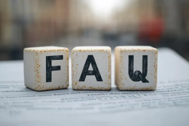 Three white cubes marked FAQ rest on a printed document with blurred background text lines.