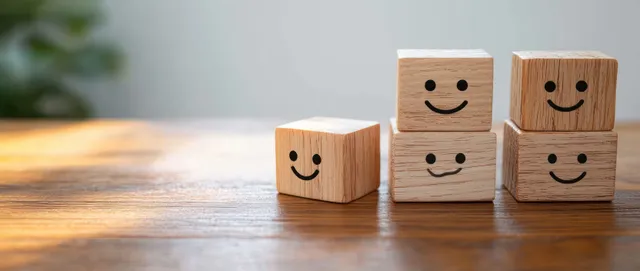 Smiling wooden emoticon blocks arranged on a desk, suggesting satisfaction survey feedback.