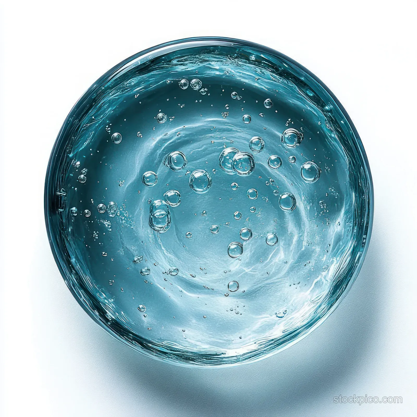 Overhead view of a clear glass filled with sparkling water, showing bubbles and ripples on a white background.