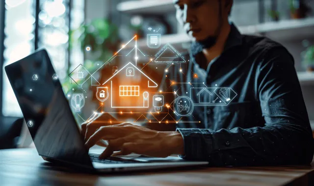 Engineer typing on a laptop with glowing smart home and renewable energy symbols overlaying the scene.