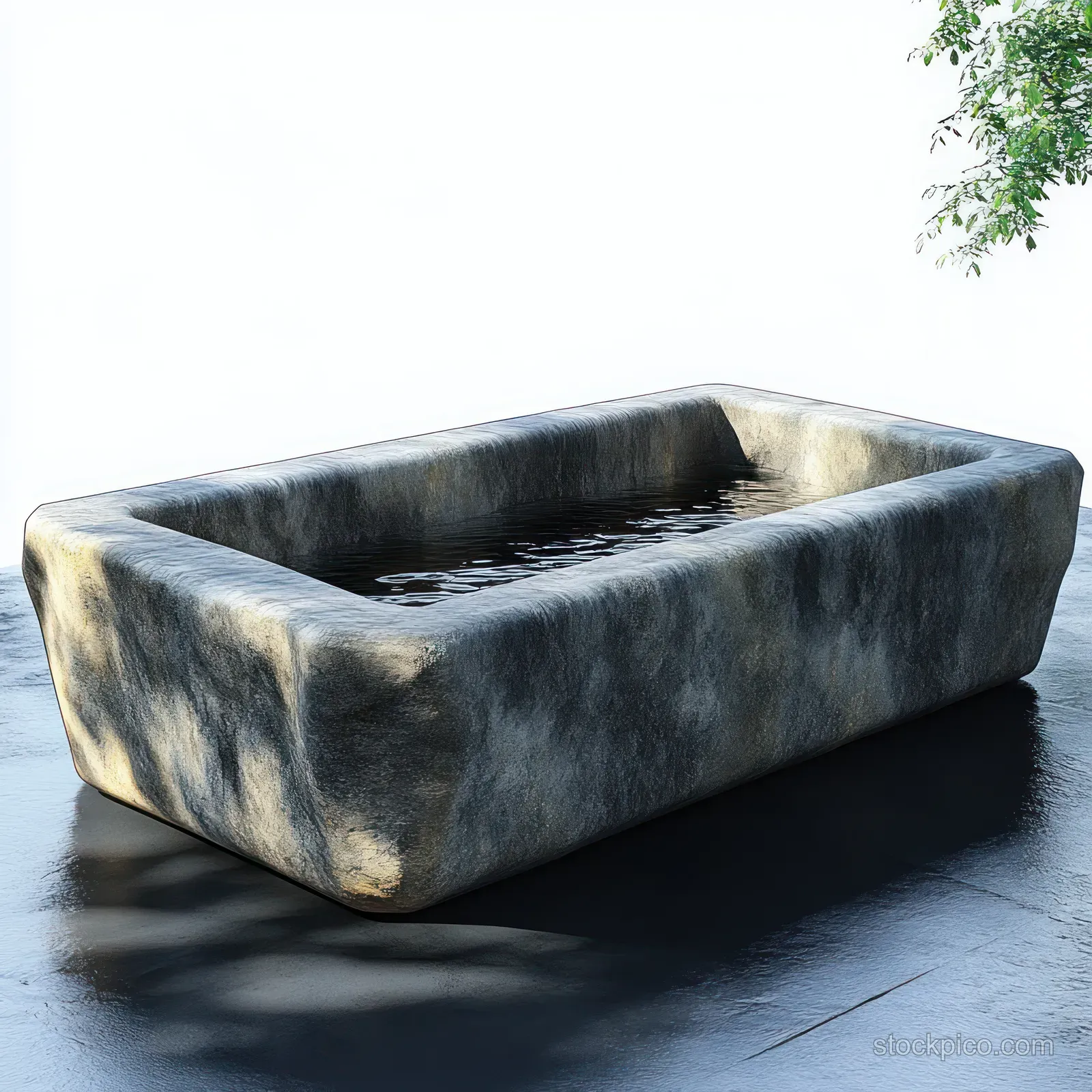 Rectangular stone basin filled with water on a dark patio, with tree-branch shadows and sunlight reflections.