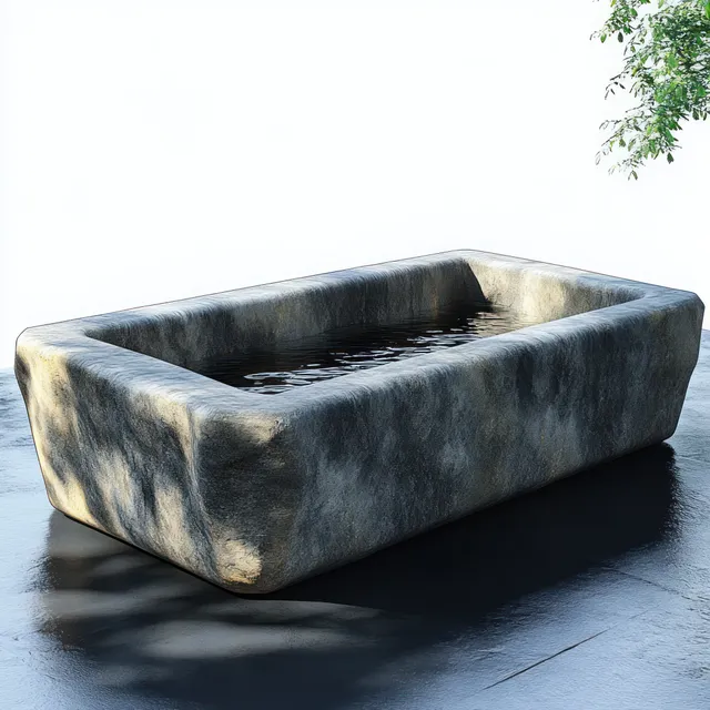 Rectangular stone basin filled with water on a dark patio, with tree-branch shadows and sunlight reflections.