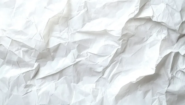 Crumpled white paper sheet with soft shadowed folds in a minimalist abstract composition