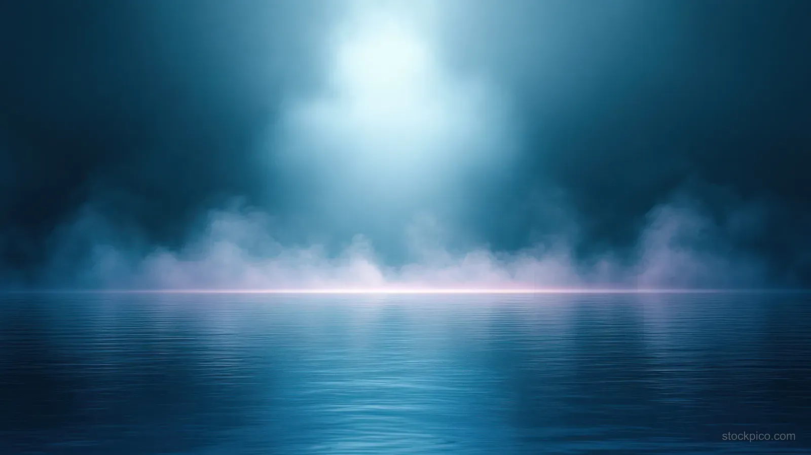 Soft blue mist hangs over a calm reflective lake as light glows along the distant horizon.