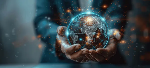 Businessman holds glowing globe with digital network icons over laptop interface