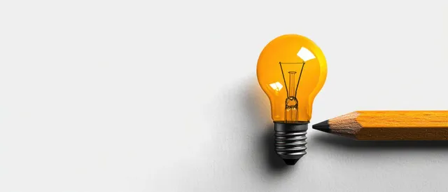 Yellow pencil and glowing amber light bulb close-up on a clean white surface