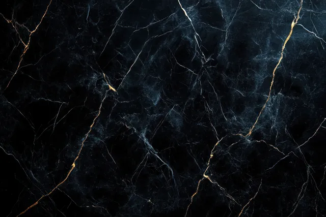 Polished black marble close-up with thin white and gold veins creating flowing natural patterns.
