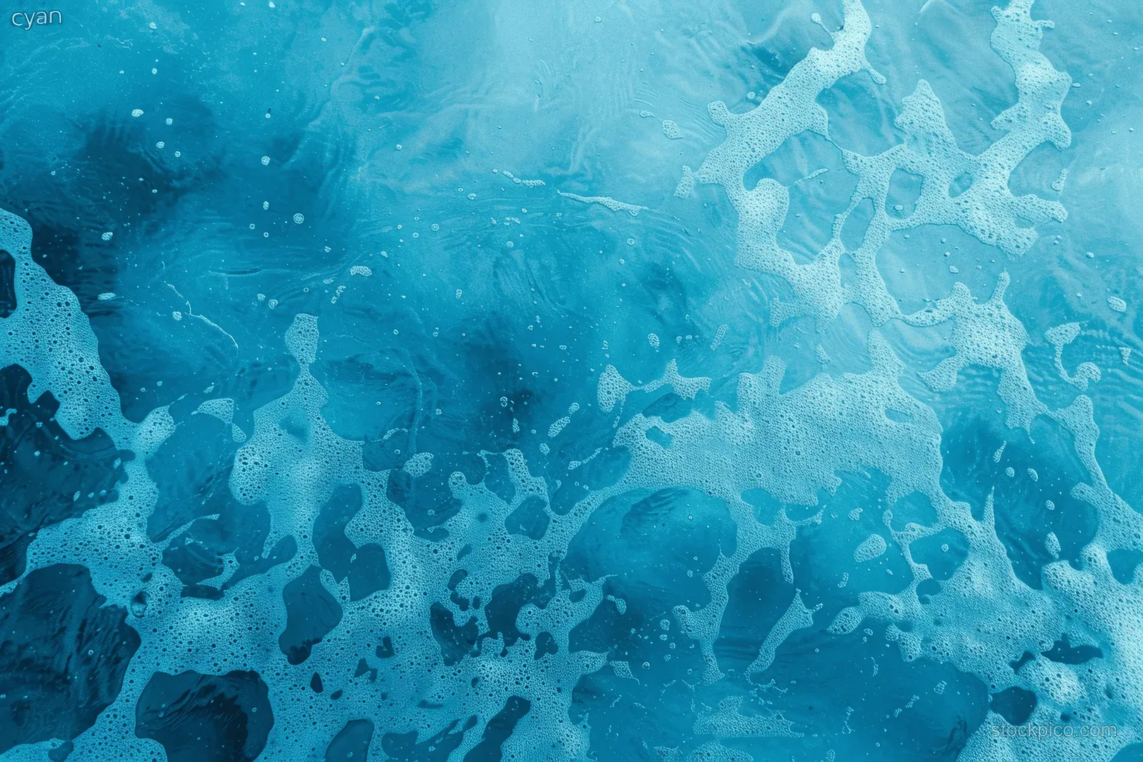 Top-down cyan ocean surface with foamy wave patterns and ripples across the water.